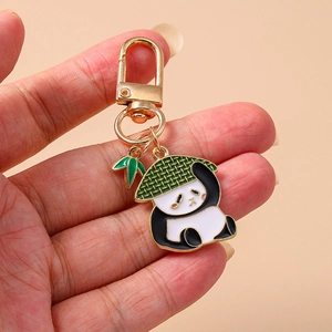 Détail d'un porte-clés panda en émail avec un chapeau de paille et un pendentif bambou