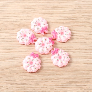 Détail de breloques donuts en résine rose avec nœuds et pépites colorées pour DIY