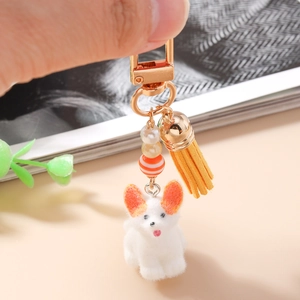 Détail d'un porte-clés chien mignon avec pompon orange et pendentif en perles