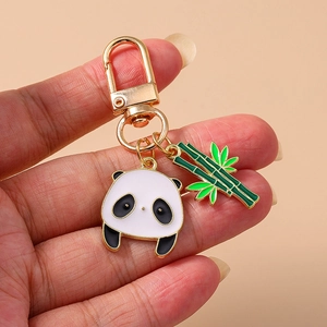 Détail d'un porte-clés panda et bambou avec fermoir en métal doré tenu dans la main d'un expert
