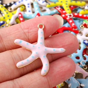 Detail van een roze emaille zeester hanger met blauwe stippen en goudlegering rand