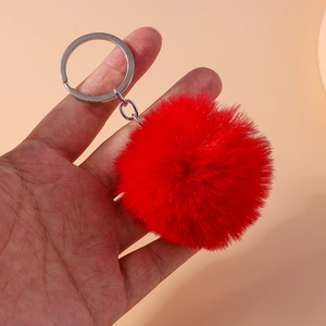 Detail of soft 8cm red faux fur pompom keychain with silver metal ring on hand