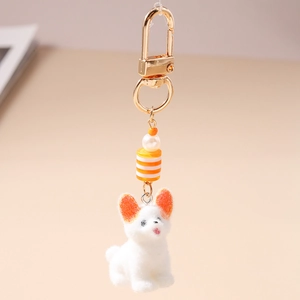Détail d'un porte-clés chien blanc floqué avec perle d'imitation et fermoir doré