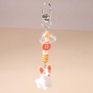 Détail d'un porte-clés chien en peluche avec perles et cloche transparente sur fermoir