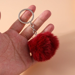Close-up of fluffy burgundy 8cm faux fur pompom keychain with silver metal clip