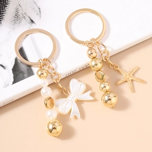 Porte-clés perles tendance avec nœud blanc et pendentif étoile de mer dorée élégant
