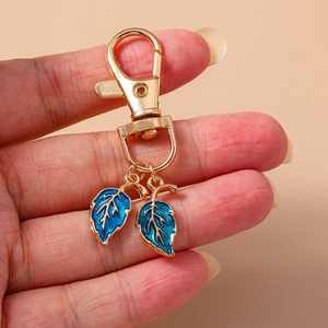 Porte-clés créatif en métal doré avec deux pendentifs de feuilles en émail bleu et fermoir
