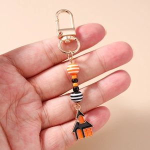 Close-up of Halloween beaded keychain featuring a haunted house enamel pendant and gold clip