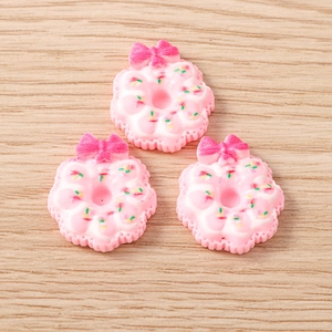 Détail de charmes donuts en résine rose avec nœuds et pépites colorées pour DIY créatif