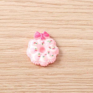 Détail d'une breloque donut en résine rose avec nœud et pépites pour créations DIY