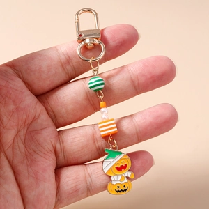 Macro detail of Halloween pumpkin mummy pendant with striped beads and golden clasp