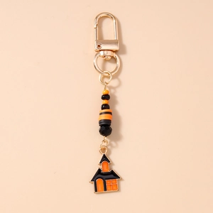 Close-up of Halloween keychain with orange beads and haunted house enamel pendant