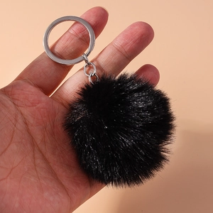Close-up of soft black faux fur pompom keychain with silver metal ring for bags