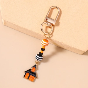 Close-up of Halloween keychain with striped beads and enamel haunted house pendant