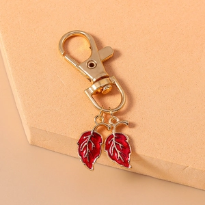 Détail du fermoir mousqueton doré avec pendentifs feuilles en émail rouge et veines dorées