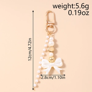 Detail of Y2K pearl keychain with white bow charm and golden metal hardware components