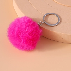 Close-up of fluffy bright rose red faux fur pompom keychain with polished silver metal ring