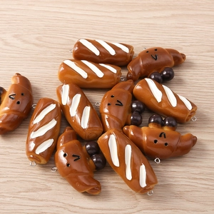 Detailed view of artificial croissant and baguette pendants with smiley faces for DIY jewelry