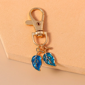 Gros plan sur un porte-clés doré orné de deux pendentifs en émail bleu en forme de feuille