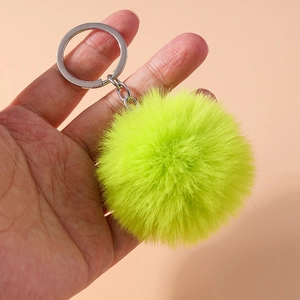 Detail shot of a vibrant lime green faux fur pompom keychain with a silver metal ring