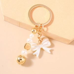 Gros plan d'un porte-clés perles avec nœud blanc sur un socle en pierre beige