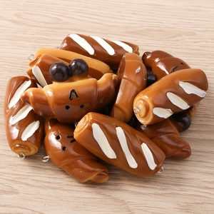 Macro shot of assorted resin food charms shaped like tiny croissants and baguettes