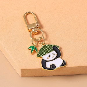 Détail d'un porte-clés panda doré avec une feuille de bambou sur une surface orange