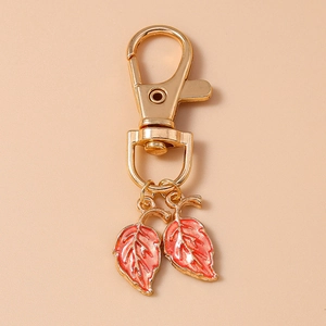 Détail d'un porte-clés doré orné de deux pendentifs en forme de feuilles en émail orange