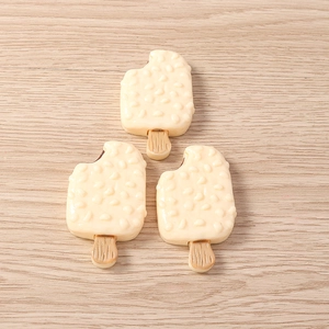 Vista detallada superior de dijes de resina de helado blanco crema con palos de madera