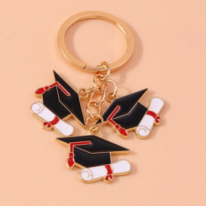 Detailed close-up of golden graduation keychain with black mortarboard and white diploma