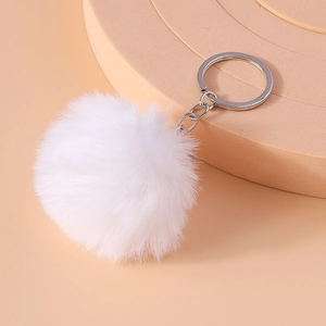Detail shot of a soft white faux fur pompom keychain with a silver metal link and ring