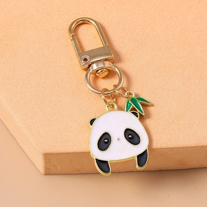Gros plan d'un porte-clés panda en émail avec charme de bambou sur un podium rose