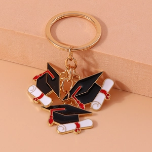 Close-up of graduation keychain with doctoral caps and diploma scrolls on gold zinc alloy