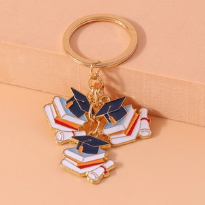 Detail of gold alloy graduation keychain with blue cap, books and diploma scroll charms