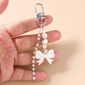 Detailed view of handmade Y2K beaded bow pearl keychain accessory held in hand