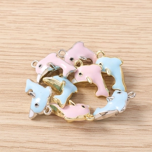 Detailopname van roze en blauwe dolfijn hangers met gouden rand en metalen oogjes