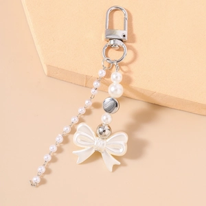Macro view of beaded pearl keychain with a bow pendant and silver polished metal clasp