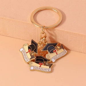 Macro detail of golden graduation keychain with graduate diploma and mortarboard charms