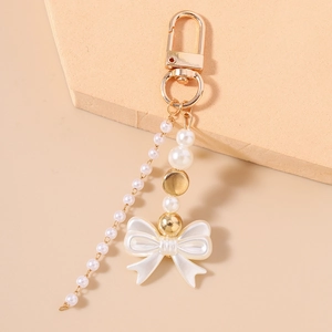 Close-up of elegant white pearl beads and resin bowknot on a gold keychain