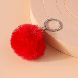 Detail view of a fluffy red faux fur pompom keychain with a polished silver ring