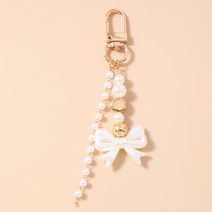 Close-up of Y2K pearl keychain featuring a white silk bow and golden lobster clasp