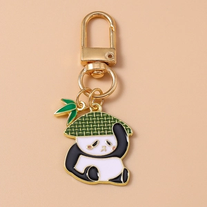 Détail d'un porte-clés panda avec chapeau vert et breloque feuille de bambou dorée