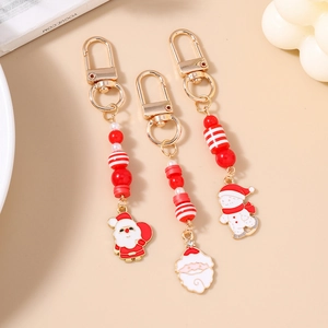 Three festive Christmas beaded keychains with Santa Claus charms on a warm cream background