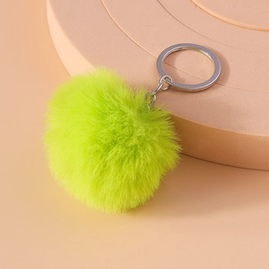 Detail of neon green faux fur pompom keychain with silver metal ring on a display stand