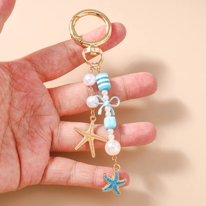 Detailopname van mode sleutelhanger met schelp en zeester vastgehouden in hand
