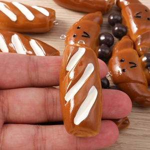Macro shot of realistic resin bread pendants including baguette and croissant for DIY jewelry