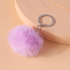 Detail of soft 8cm faux fur lavender pom pom keychain with silver metal ring on light pink stand