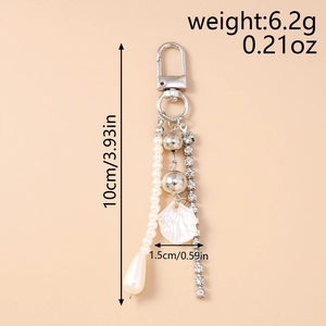 Detail of keychain showing white pearl strand, shell charm, and rhinestone tassel chain
