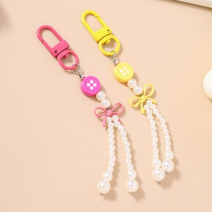 Détail des porte-clés à pompons en perles avec boutons et nœuds en rose et jaune