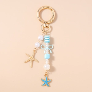 Detail van nautische sleutelhanger met gouden zeester bedeltjes en witte parels in blauw